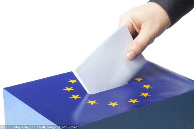 Dieses Bild zeigt eine Wahlurne mit dem Logo der Europäischen Union, in die ein Stimmzettel eingeworfen wird. © ericsphotography / E+ / Getty Images / 173827165
